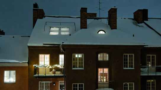 Husfasad i mörker där det lyser i fönstren