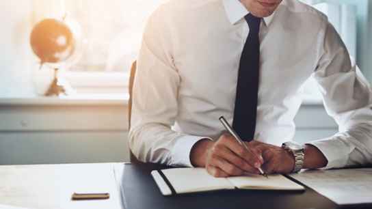 Man i vit skjorta och slips läser dokument